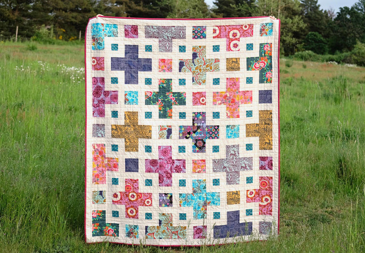 The Violet Quilt displayed in a vibrant design, now updated with queen and king sizes. Featuring bold fabrics and a versatile layout, this quilt showcases its adaptability for various color palettes and fabric styles.